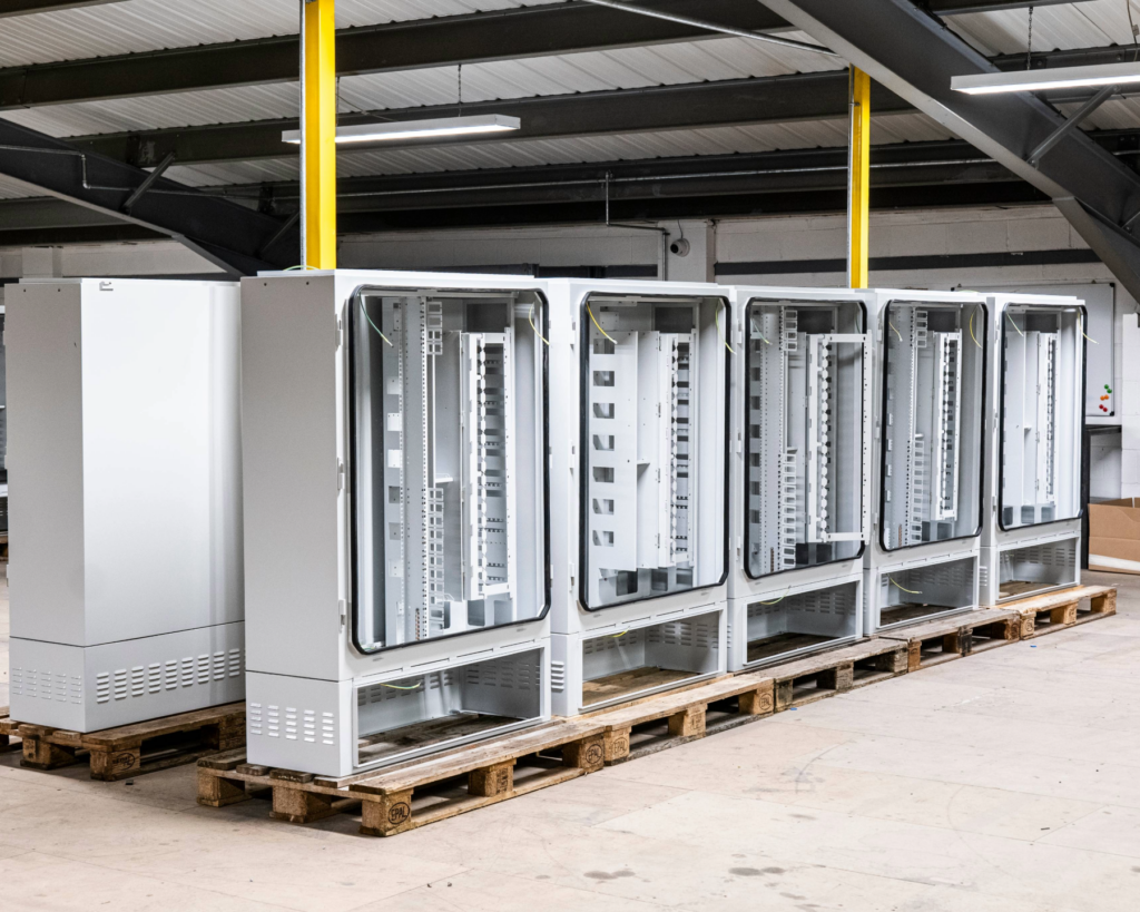 A row of grey telecom cabinets being assembled